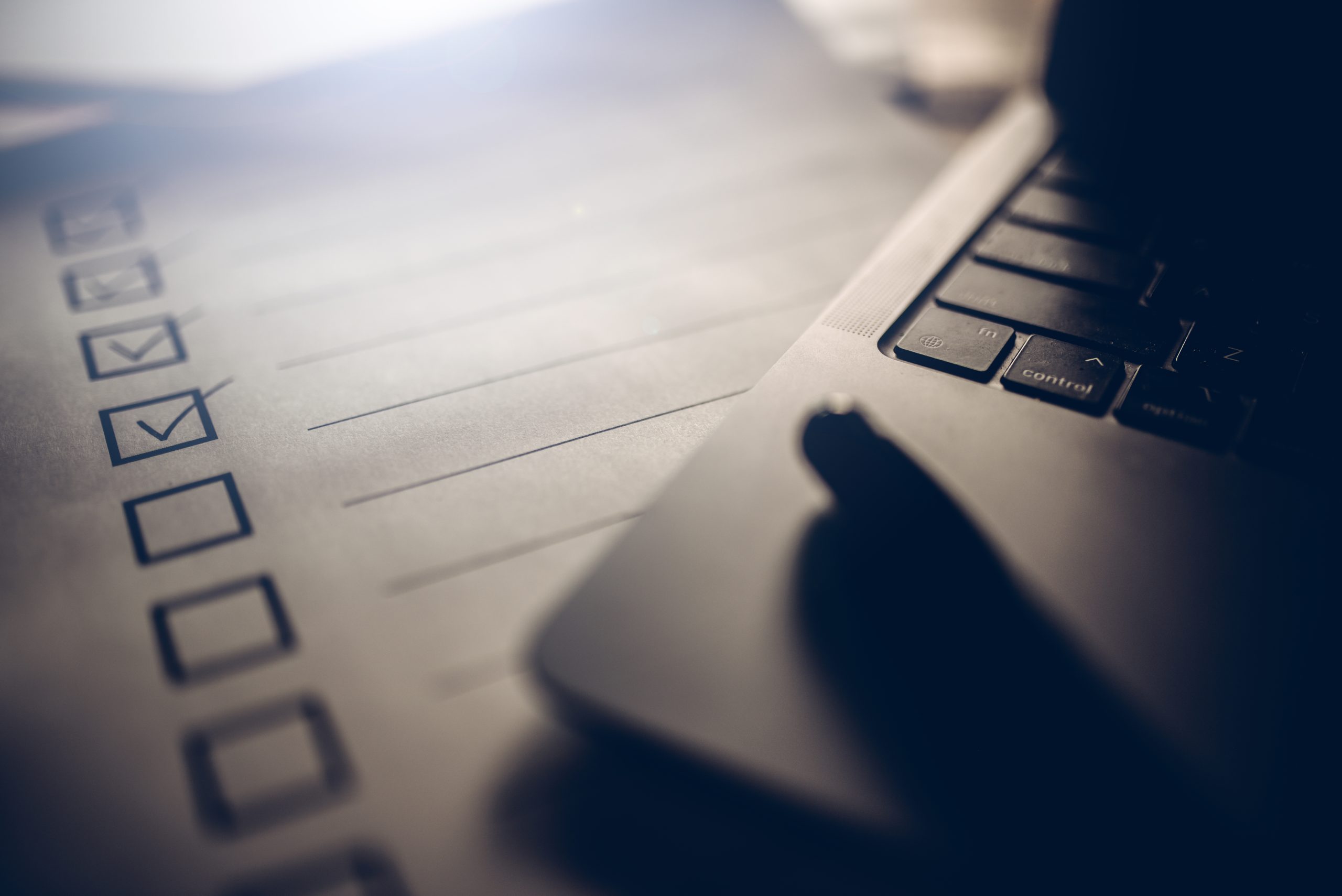 Paper checklist sitting next to a laptop computer