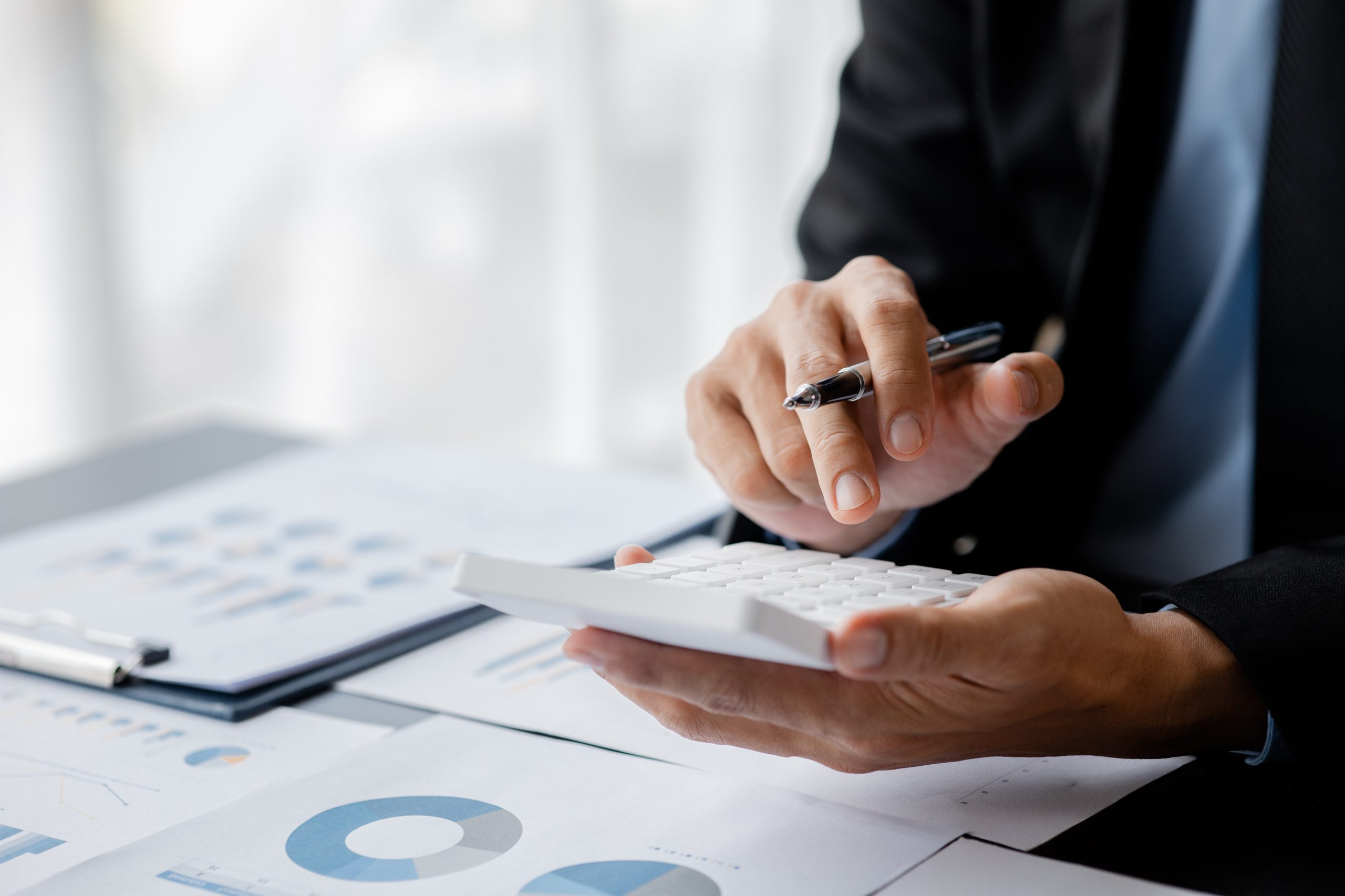 Businessman is using a calculator to calculate company financial figures